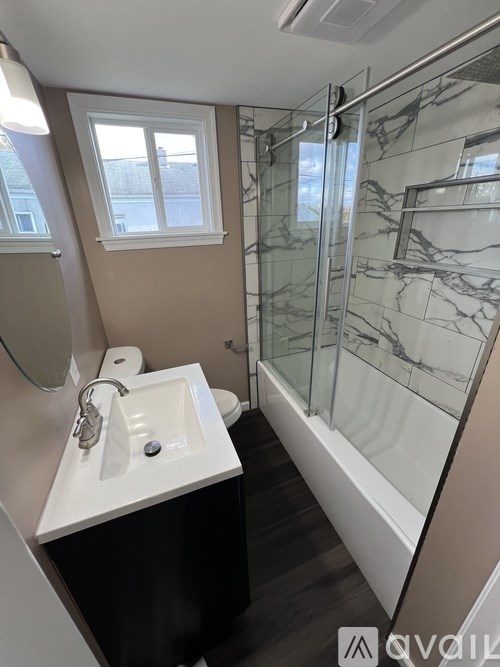 A bathroom with a marble shower and a white sink.