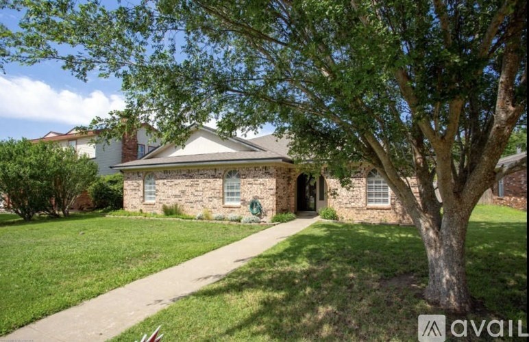A house with a stone facade and a large tree in front.