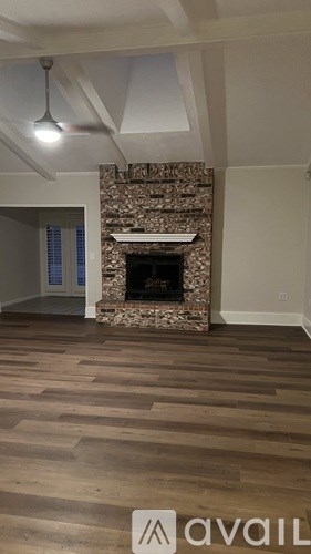 A room with a stone fireplace and wooden flooring.
