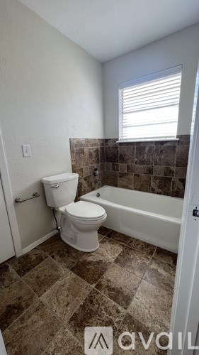 A bathroom with a toilet, tub, and tiled floor.
