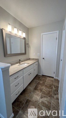 A bathroom with a sink, mirror, and tiled floor.