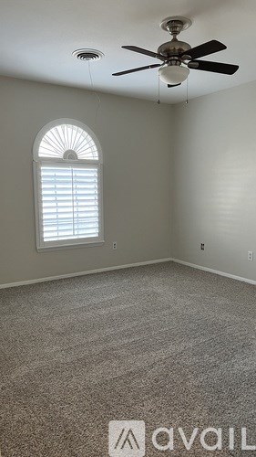 A room with a fan, carpet, and a window.