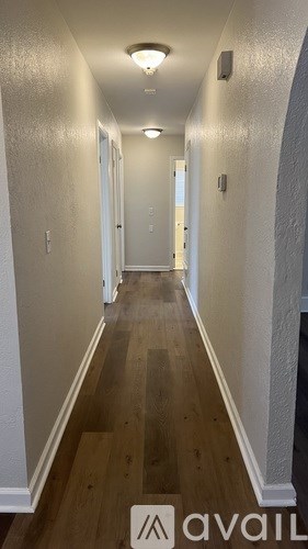 A long hallway with wood floors and white walls.