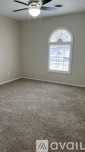 A room with a carpeted floor, a ceiling fan, and a window with blinds.