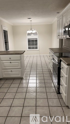 A kitchen with white cabinets and black tile flooring.
