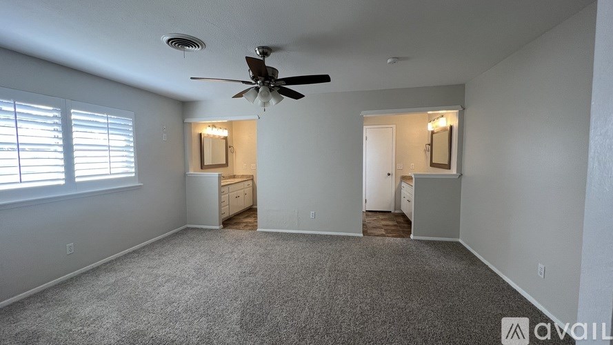 A spacious room with a ceiling fan and carpeted floor.