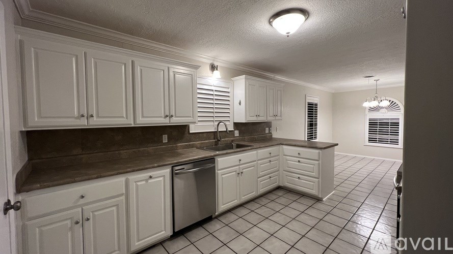 A kitchen with white cabinets and a brown countertop.