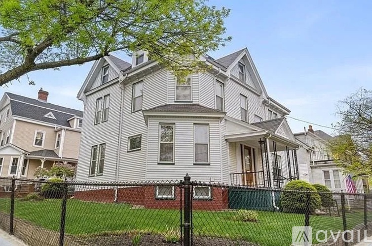A large, two-story house with a grey exterior and a black fence in front.