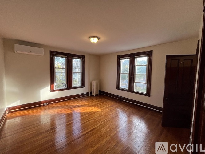 A room with wooden floors and two windows.