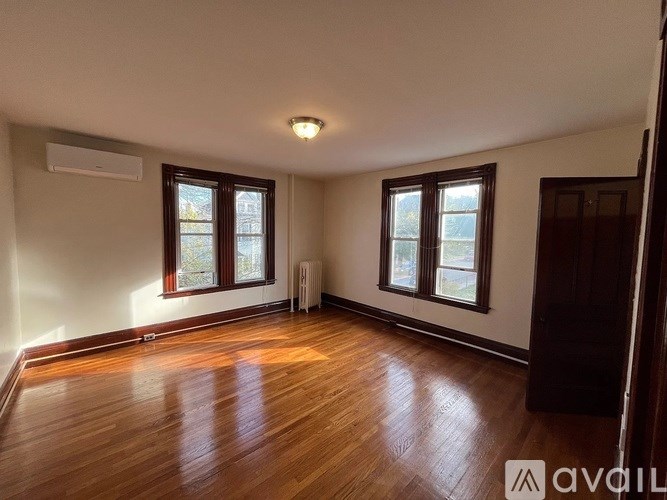 A room with wooden floors and two windows.