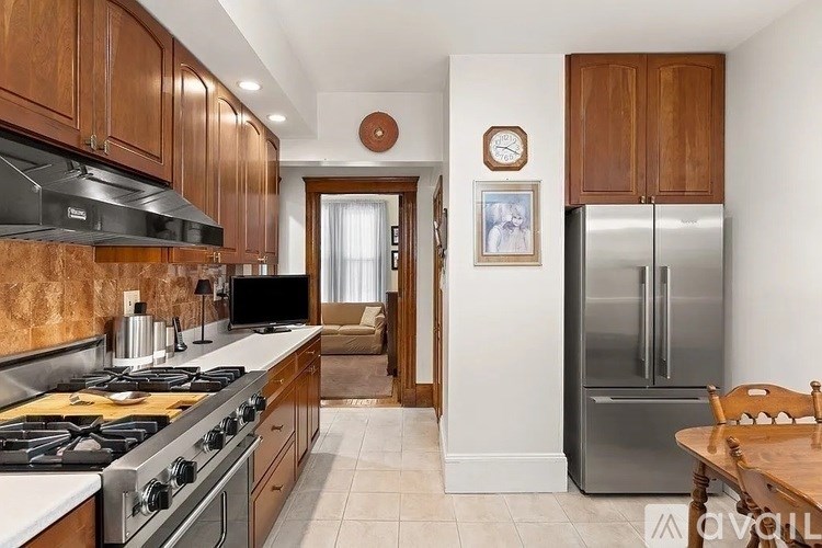 A kitchen with wooden cabinets and a stainless steel refrigerator.
