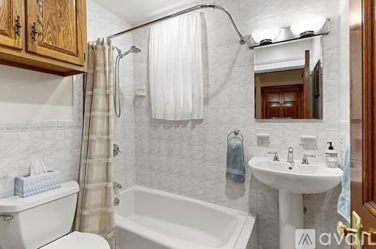 A bathroom with a white tub, sink, and toilet.