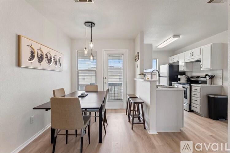 A kitchen with a dining table and chairs in the foreground and a kitchen island in the background.