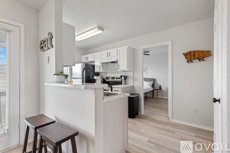 A kitchen with white cabinets and a black fridge.