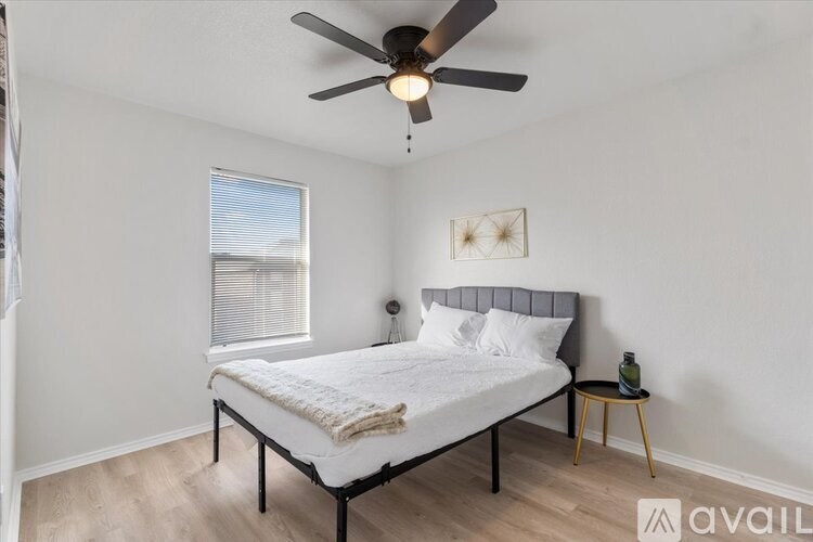 A bedroom with a bed, a small table, and a ceiling fan.