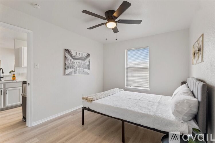 A bedroom with a bed, a ceiling fan, and a picture on the wall.