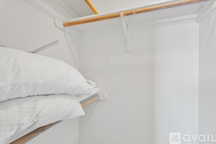 A white pillow is on a bed with a white sheet.