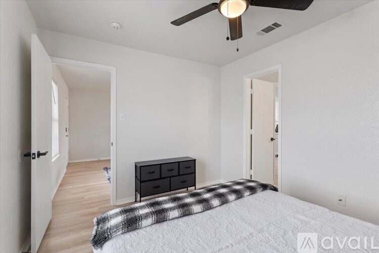 A bedroom with a bed, dresser, and ceiling fan.