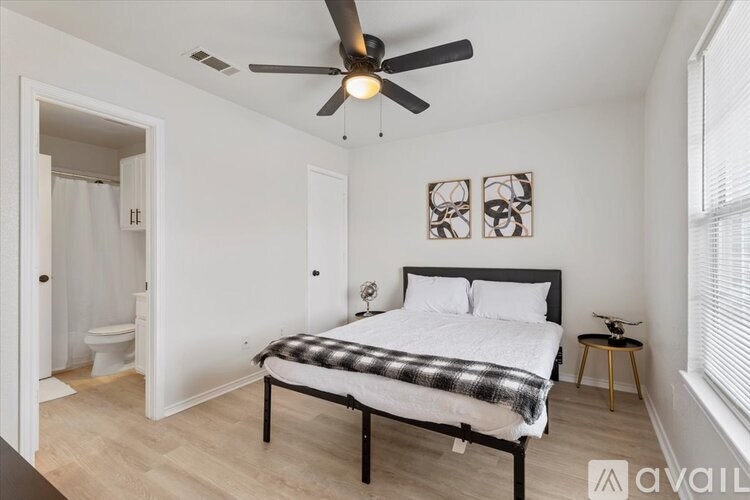 A bedroom with a bed, a ceiling fan, and a small table.