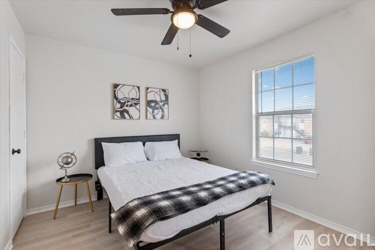 A bedroom with a bed, a ceiling fan, and a window.