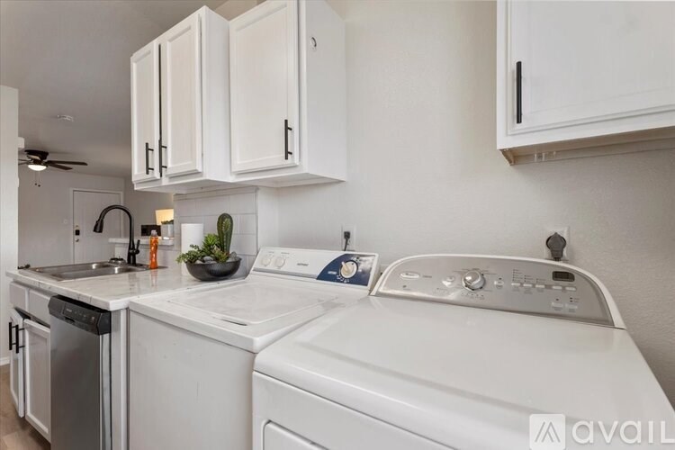 A white washing machine in a kitchen with white cabinets.