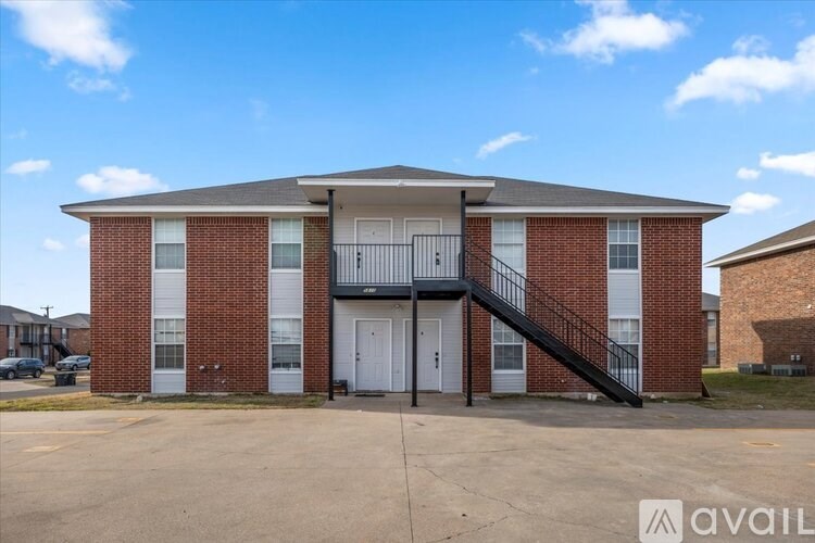A red brick apartment building with a black metal staircase leading to the second floor.