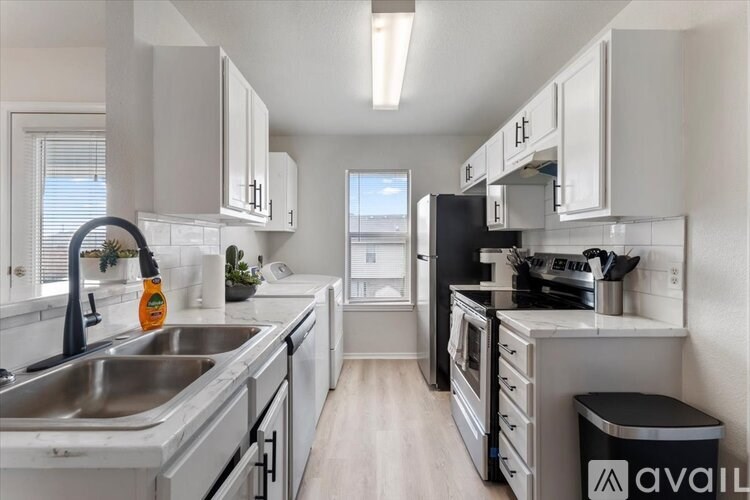 A kitchen with white cabinets and a black fridge.