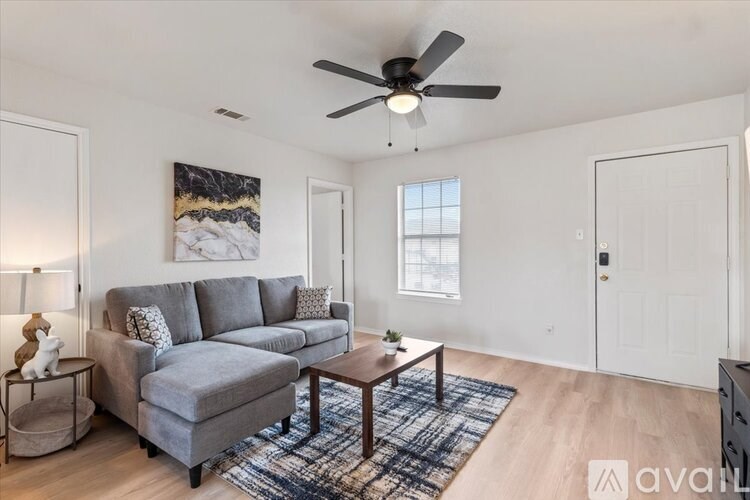 A living room with a grey couch, a wooden coffee table, and a ceiling fan.