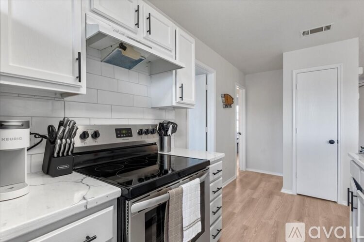 A kitchen with white cabinets and a black stove top.