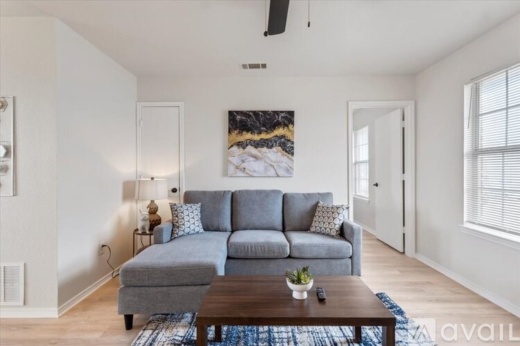 A living room with a grey couch and a painting on the wall.