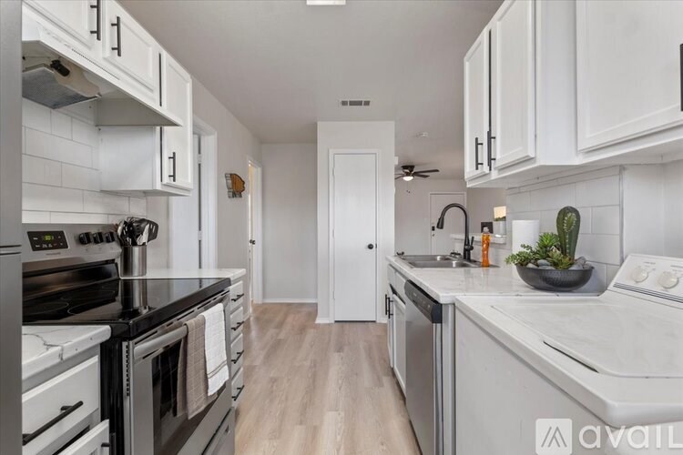 A modern kitchen with white cabinets and stainless steel appliances.