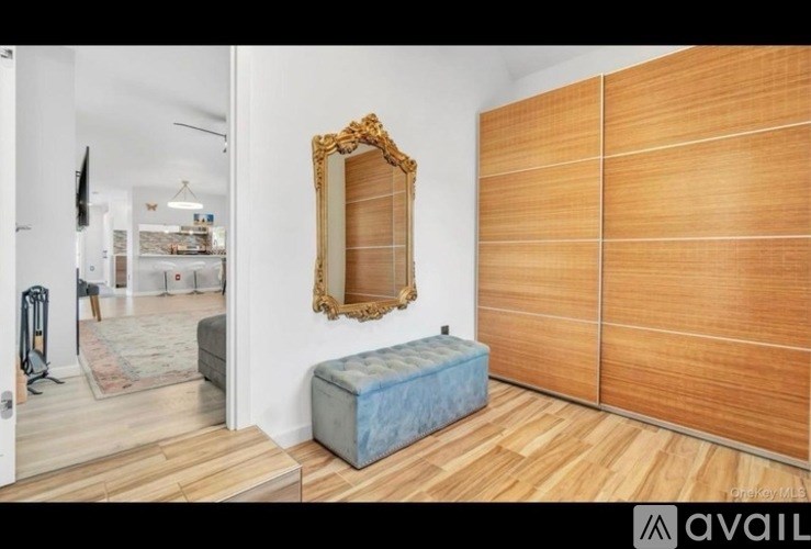 A room with a wooden floor, a mirror, and a bench.