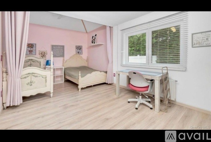 A pink bedroom with a bed, desk, and chair.