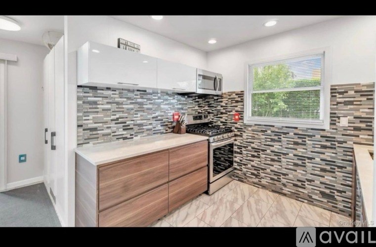 A kitchen with a stone backsplash and wooden cabinets.