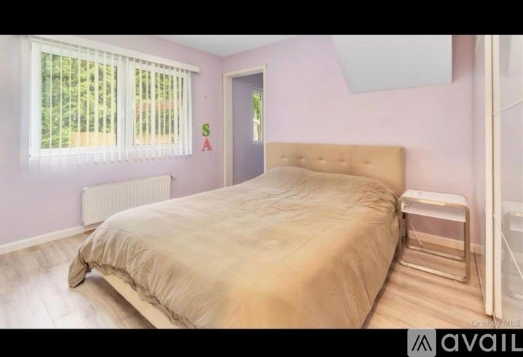 A bedroom with a bed, a window with blinds, and a door.