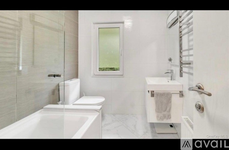 A white bathroom with a tub, toilet, and sink.