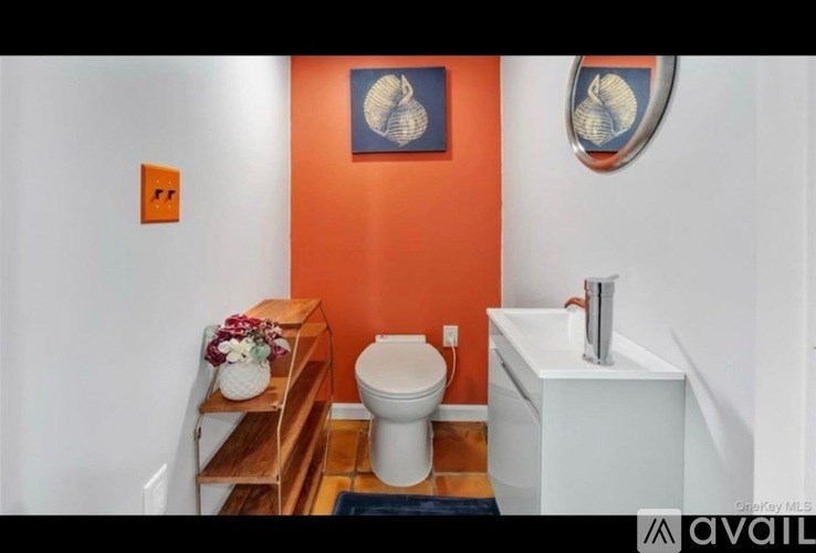A bathroom with orange walls and a white toilet and sink.