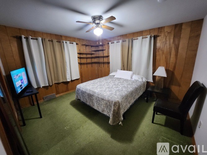 A bedroom with a bed, chair, and television.
