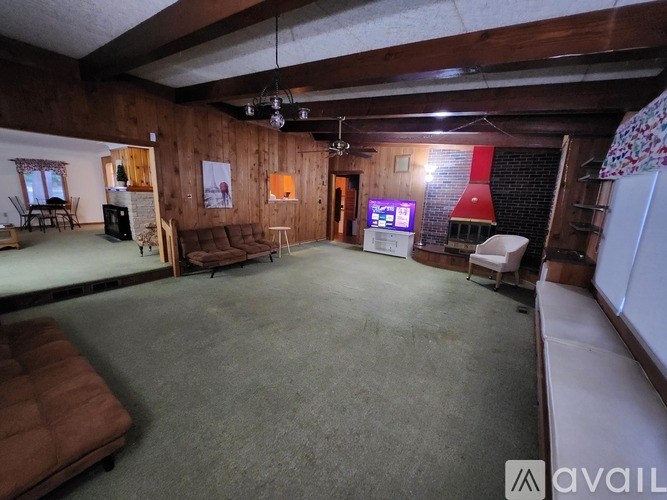 A spacious room with a couch, a chair, a table, and a TV.