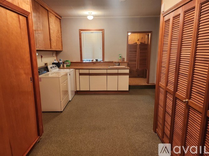 A kitchen with wooden cabinets and a carpeted floor.