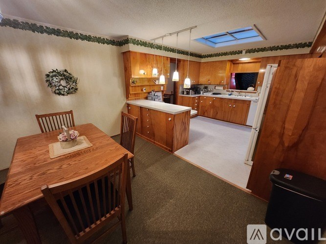A kitchen with a table and chairs in the foreground and a refrigerator in the background.
