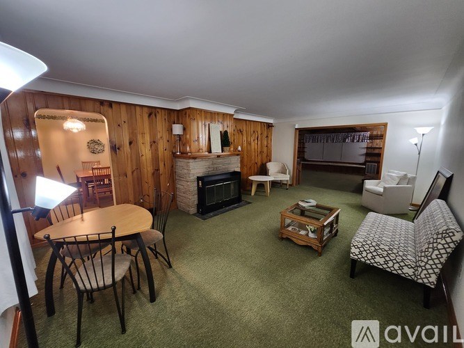 A living room with a wooden wall and a green carpet.