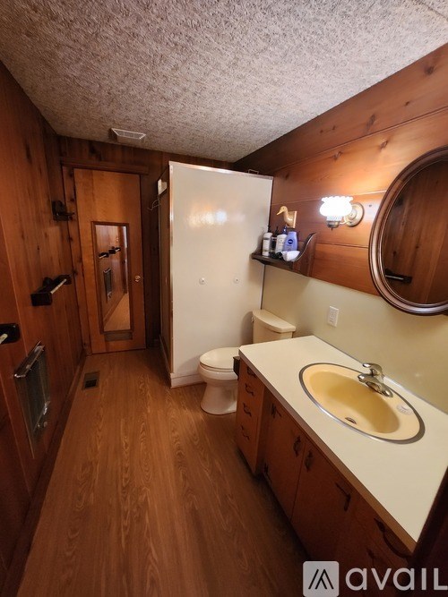 A bathroom with a toilet, sink, and wooden cabinets.