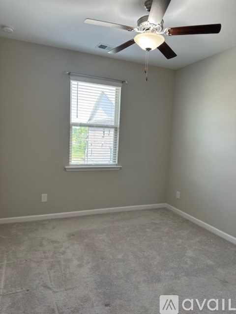 A room with a ceiling fan and a window with blinds.