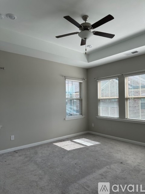 A room with a ceiling fan and two windows.