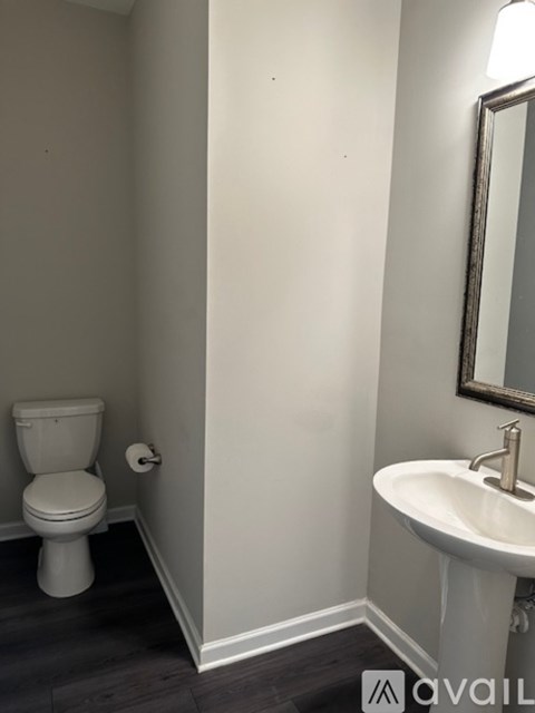 A white toilet sits next to a white sink in a small bathroom.