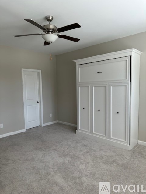 A room with a ceiling fan and a large white wardrobe.