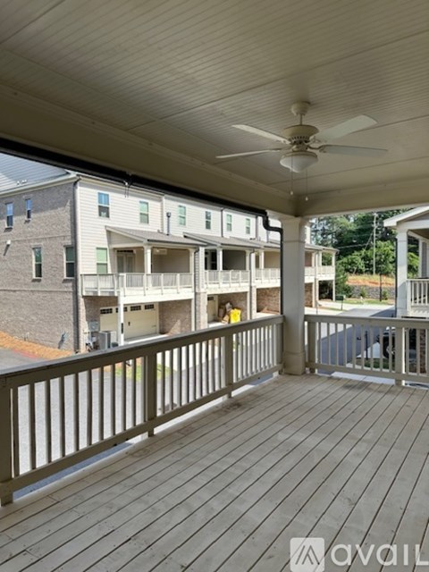 A balcony with a ceiling fan and wooden flooring.