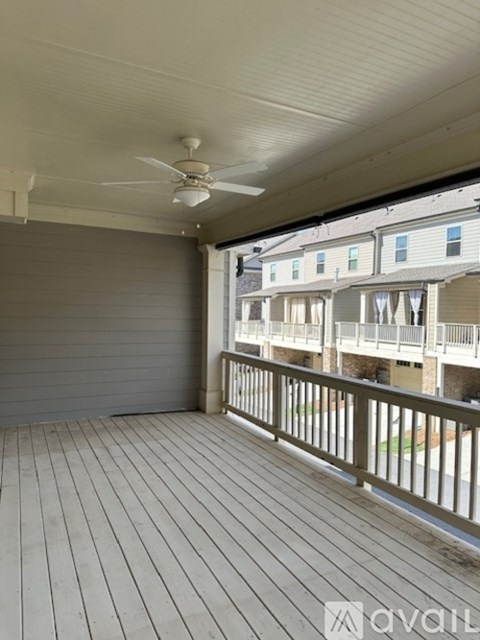 A balcony with a fan and a view of apartment buildings.