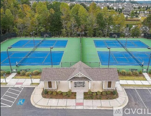 A tennis court surrounded by trees and a small building.